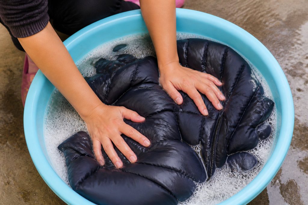 Doudoune lavée à la main dans une bassine d’eau tiède savonneuse