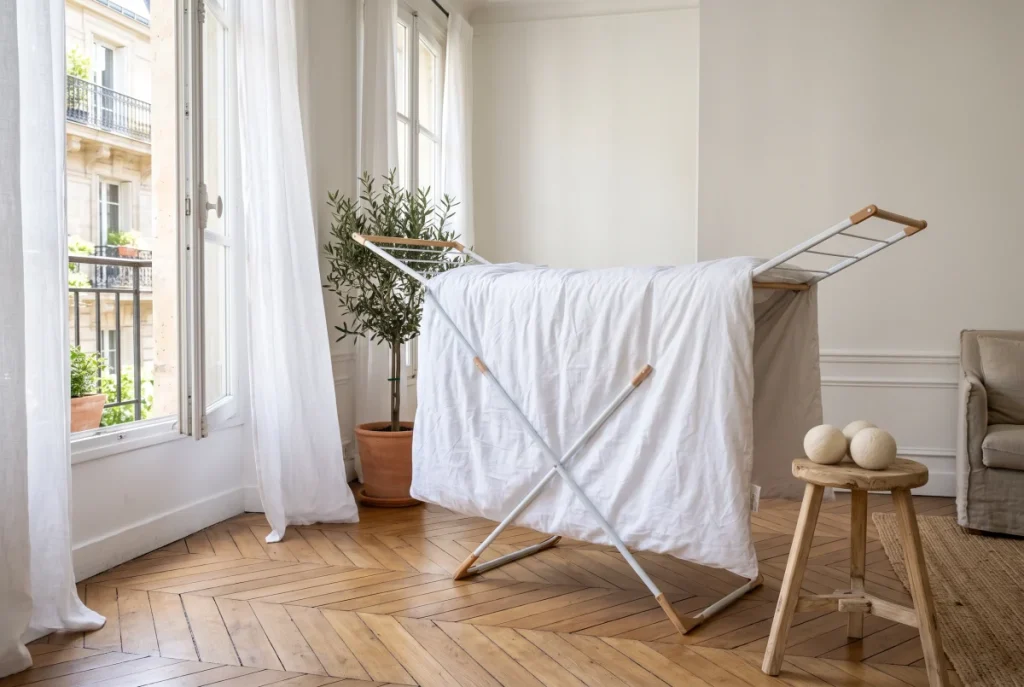 Couette lavée qui sèche sur un étendoir près d’une fenêtre ouverte